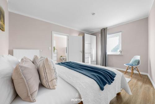 a white bedroom with a bed with pillows and a chair at Ferienwohnung Windjammer 5 St Peter-Ording in Sankt Peter-Ording