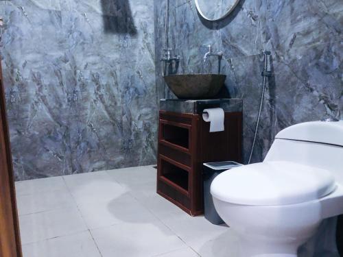 a bathroom with a sink and a toilet and a bowl at Pondok Kakiang in Pulukan