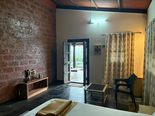 ein Schlafzimmer mit einem Bett, einem Tisch und einem Stuhl in der Unterkunft Vanacara in Sawantwadi