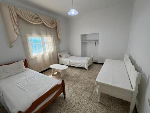 a bedroom with two beds and a table in it at Charmante maison à Hammamet, proche plage et commodités in Hammamet