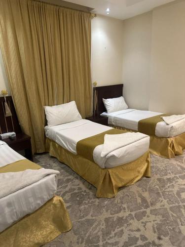 a hotel room with two beds in a room at غرف تاج الذهبية الملاوي in Mecca
