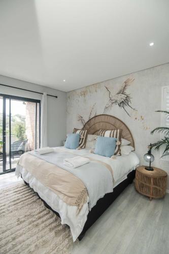 a bedroom with a large bed and a wall with a bird mural at Lovemore Retreat in Gqeberha