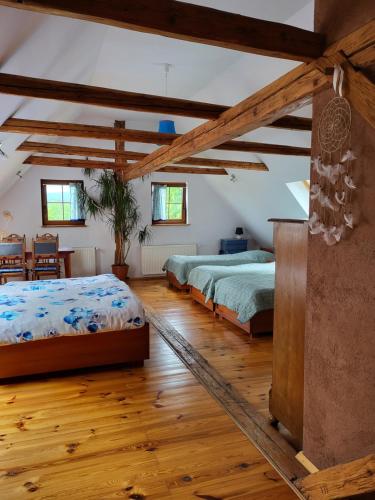 two beds in a room with wooden floors and beams at Gajowe Zacisze in Mirsk