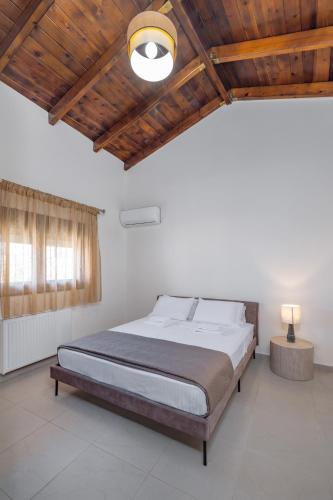 a bedroom with a large bed with a wooden ceiling at TheraLiving - Boutique Apartment with Balcony in Afantou
