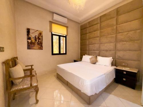 a bedroom with a large white bed and a chair at Nassau House Marrakech in Mellah Bakka