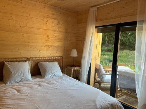 a bedroom with a bed and a sliding glass door at Les Ecolodges du Lac in Chambon-sur-Lac