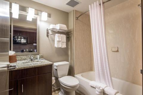 a bathroom with a toilet and a sink and a tub at Suburban Studios Midland I-20 in Midland