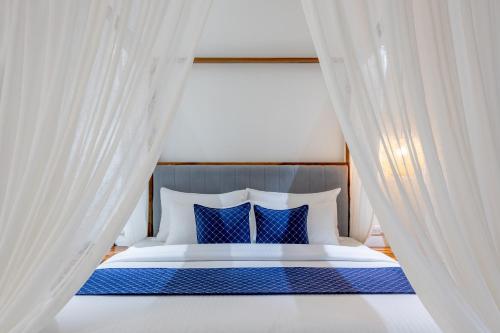 a bed with blue and white pillows and curtains at Aayovea Resort Ayodhya Near Ram Mandir & Saryu River in Ayodhya