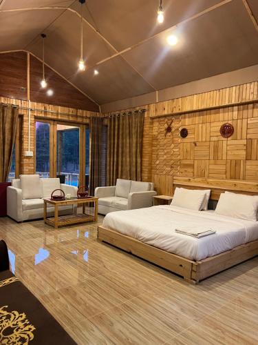 a bedroom with a bed and two chairs and a table at Relax Cottages & Resort Kalam in Kalām