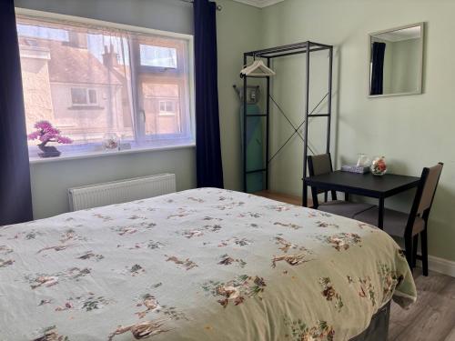 a bedroom with a bed and a table and a window at Orient Short Stay in Holyhead