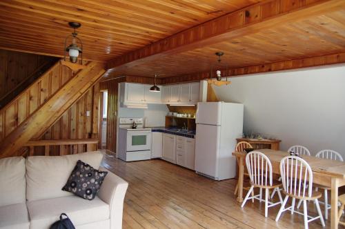 Una sala de estar con un sofá y una mesa y una cocina. en Chalet du barrage, en East Broughton Station