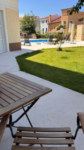 a picnic table and benches next to a lawn at Apartments Cassia in Mali Lošinj