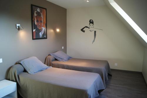 ロスコフにあるResidence Kersaliouのベッド2台が備わる部屋、壁に絵が飾られた部屋