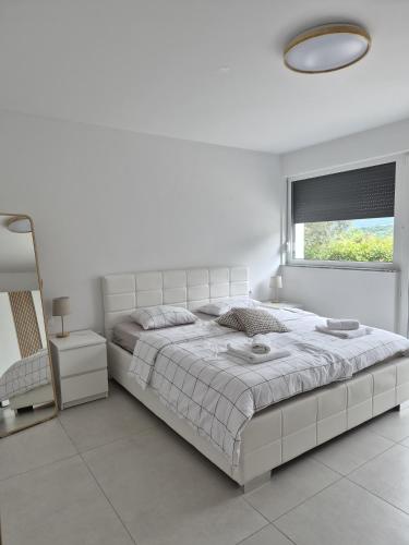 a white bedroom with a large bed and a window at Hiša Naj in Koper