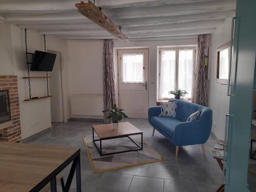 a living room with a blue couch and a table at Le lit de la SEINE in Saint-Seine-lʼAbbaye