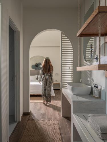 a woman walking into a bathroom with a bed at Pnoe Luxury Villa - Private Pool Retreat & BBQ in Ierissos