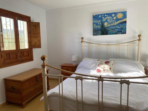 a bedroom with a bed and a painting on the wall at Stunning views, 3 bed, private pool, olive grove in Iznájar