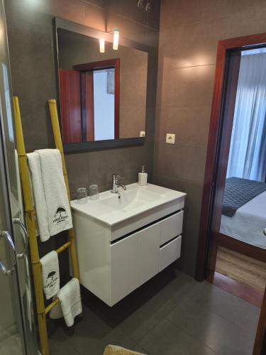 a bathroom with a sink and a mirror and a bed at Verde Pinho in Geres