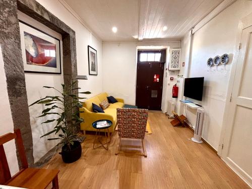 a living room with a yellow couch and a tv at Casinha do Solar in Angra do Heroísmo