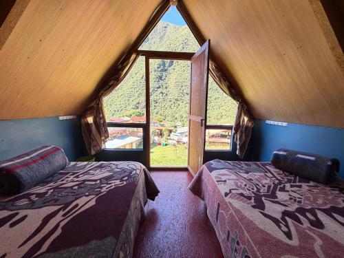 a room with two beds and a large window at Salkantay Lodge Collpapampa in Colcapampa