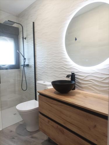 a bathroom with a sink and a toilet and a mirror at El Loft de Cris in Béjar