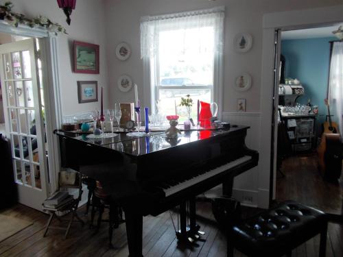 een zwarte piano in een woonkamer met een raam bij Margaree Harbour View Inn B&B in Margaree Harbour