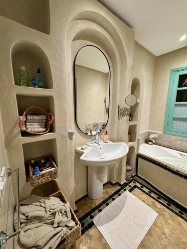 a bathroom with a sink and a tub and a mirror at Serene Villa with 4 Pools, Palmeraie, Marrakech in Douar Soukkane