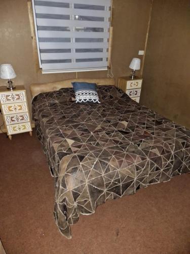 a bed in a bedroom with two night stands and a window at Cabaña Gazul in Porvenir