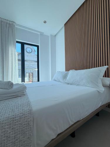 a bedroom with a large white bed with a window at Quercus in Pozoblanco