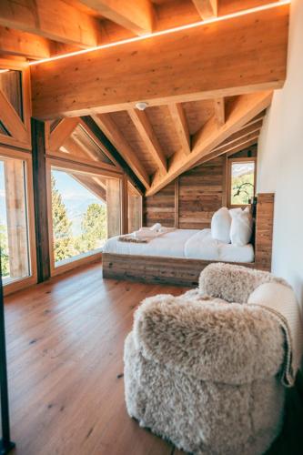 a bedroom with two beds and a chair in a room at Nînda Boutique Hôtel in Nendaz
