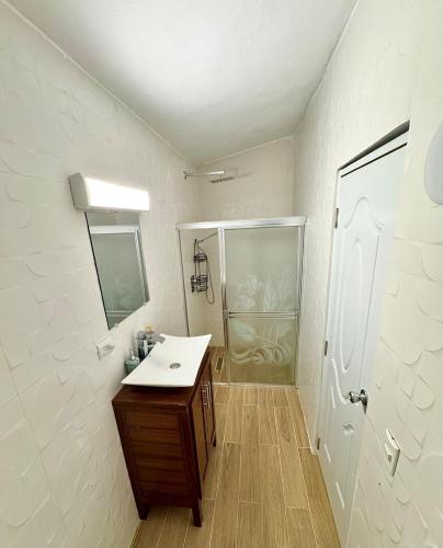 a white bathroom with a sink and a shower at Villa La Dueña Las Terrenas in Las Terrenas