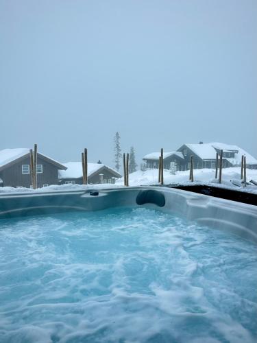 a hot tub with snow on the ground at High-standard cabin with jacuzzi & stunning views in Øyer