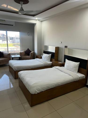 a hotel room with two beds and a couch at We Hotels in Islamabad