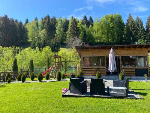 a log cabin with chairs and a playground at Cabana La Batranu-ciubar&atv in Borşa