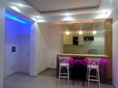 a kitchen with two stools and a bar with purple lights at Résidence Nour in Monastir