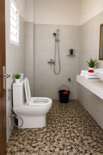a white bathroom with a toilet and a shower at Hotel National Ambanja in Ambanja