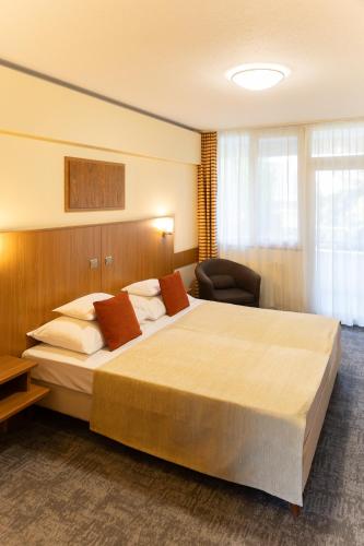 a hotel room with a large bed and a chair at Art Hotel superior in Zalakaros