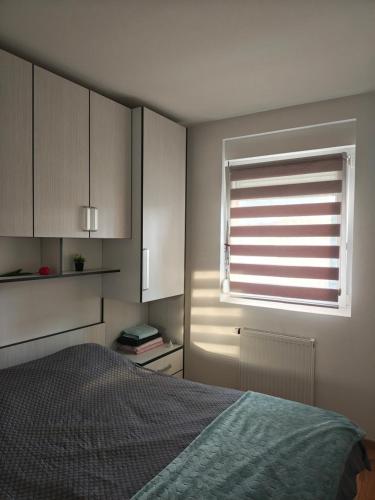 a bedroom with a bed and a window with blinds at Urban escape in Doboj