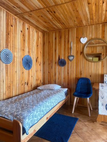 a wooden room with a bed and a blue chair at Tleniowo in Tleń