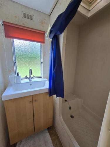 a bathroom with a sink and a window and a tub at Domki u Agi in Głęboczek