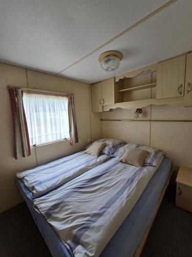 a large bed in a small room with a window at Domki u Agi in Głęboczek