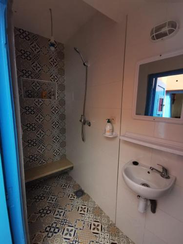 a bathroom with a sink and a shower with a window at Grotte pied dans l'eau in Aglou