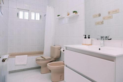 a white bathroom with a toilet and a sink at Casa Meiramar in Moaña
