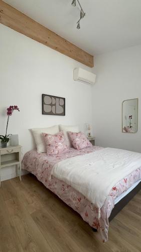 a white bedroom with a large bed with pink sheets at Les Jujubiers in Draguignan