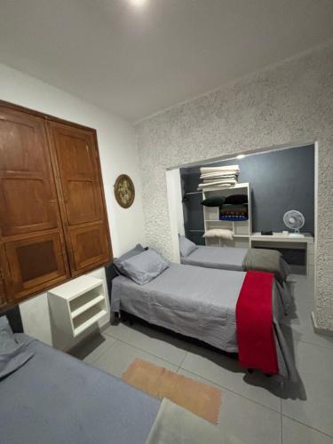 a bedroom with two beds and a desk in it at Quartos Confortáveis em Belo Horizonte in Belo Horizonte