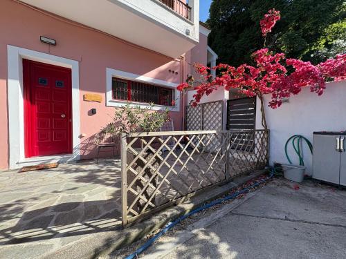 a pink house with a red door and a fence at Corfu Port Sweet Home in Mantoúkion