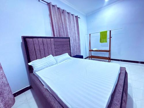 a bedroom with a large bed with white sheets at Zanzibar Apartment 1 in Kibele