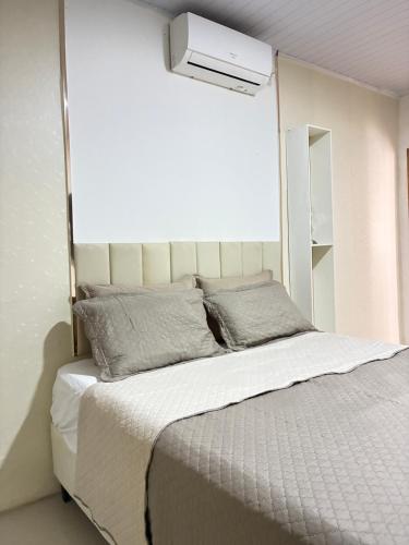 a bedroom with a large white bed with a window at Jardim Florestal Italy-Casa Jacarandá in Itaquatiara