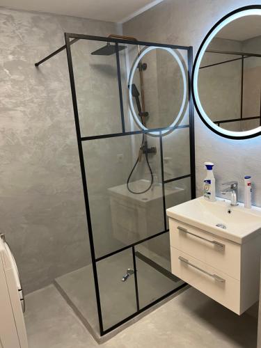 a bathroom with a glass shower with a sink and a mirror at Apartament in the center of Poprad-free parking in Poprad