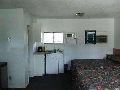 a hotel room with a bed and a small kitchen at Ponderosa Motor Inn in Golden